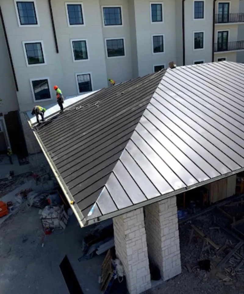 Crew installing standing seam metal roof panels on a commercial project in Tomball